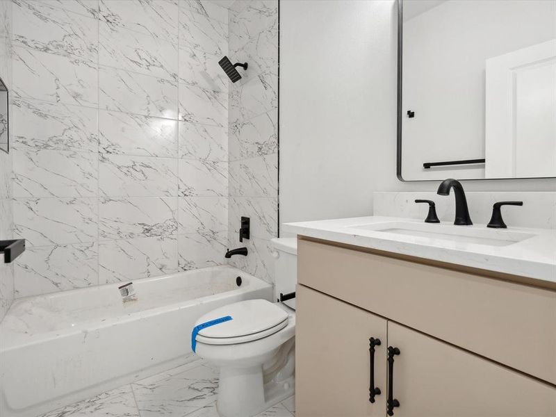 Full bathroom featuring vanity, tiled shower / bath combo, and toilet