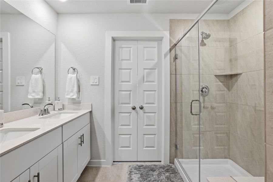 This modern Primary bathroom features a sleek double vanity with ample storage, a large mirror, and stylish fixtures.