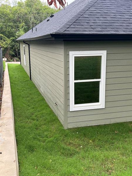 View of side of home featuring a shingled roof and a lawn View of side of home featuring a shingled roof and a lawn