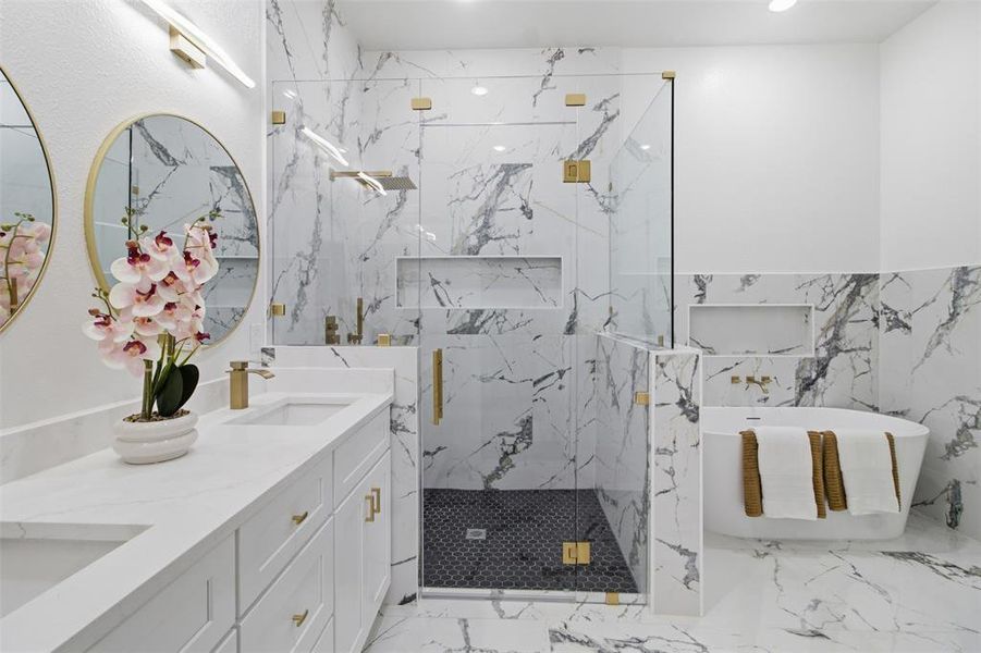 Bathroom featuring extensive marble-look tile, a freestanding soaking tub, and a glass-enclosed shower with a dark tiled floor