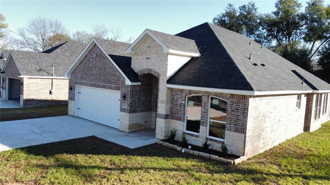 View of front of property with roof with shingles, brick siding, and a front yard