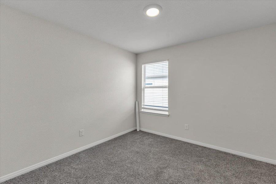 This room features neutral-toned walls, gray carpeting, and a window with blinds