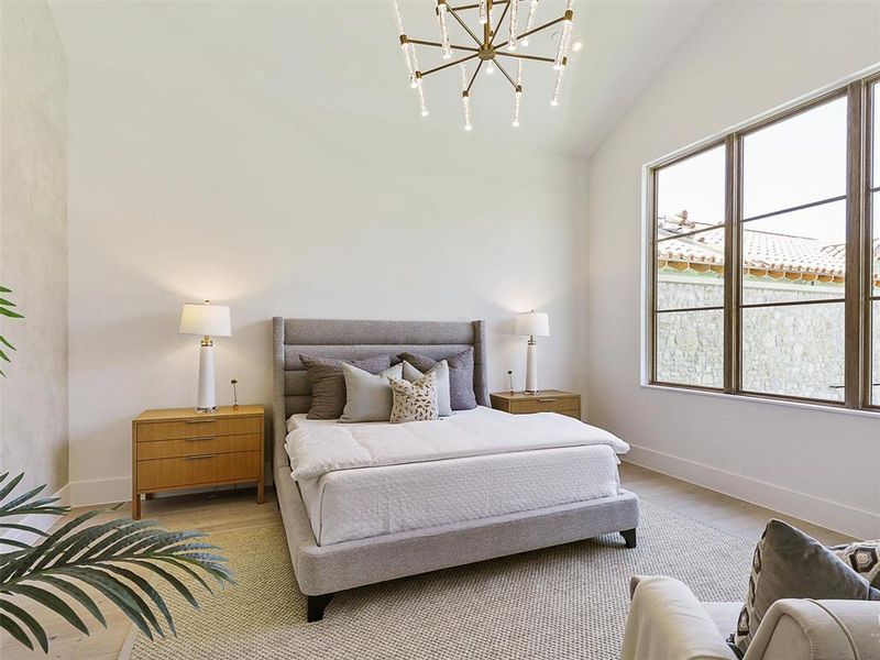 Bedroom featuring light wood-type flooring, a chandelier, and vaulted ceiling