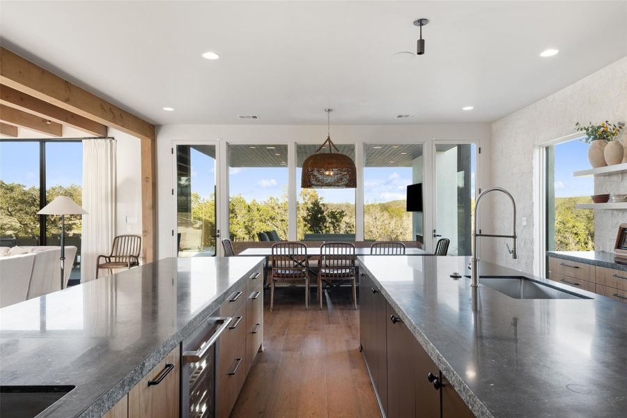 Kitchen with dark stone counters, pendant lighting, dark wood-type flooring, plenty of natural light, and recessed lighting