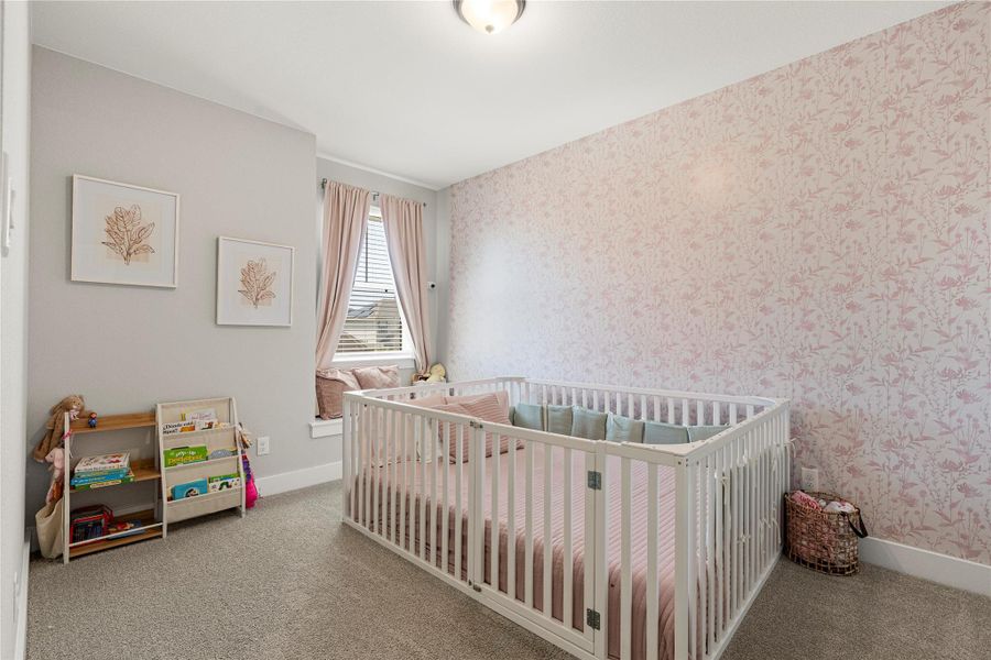 Soft floral wallpaper and window seat define a serene nursery with plush carpeting. Soft floral wallpaper and window seat define a serene nursery with plush carpeting.