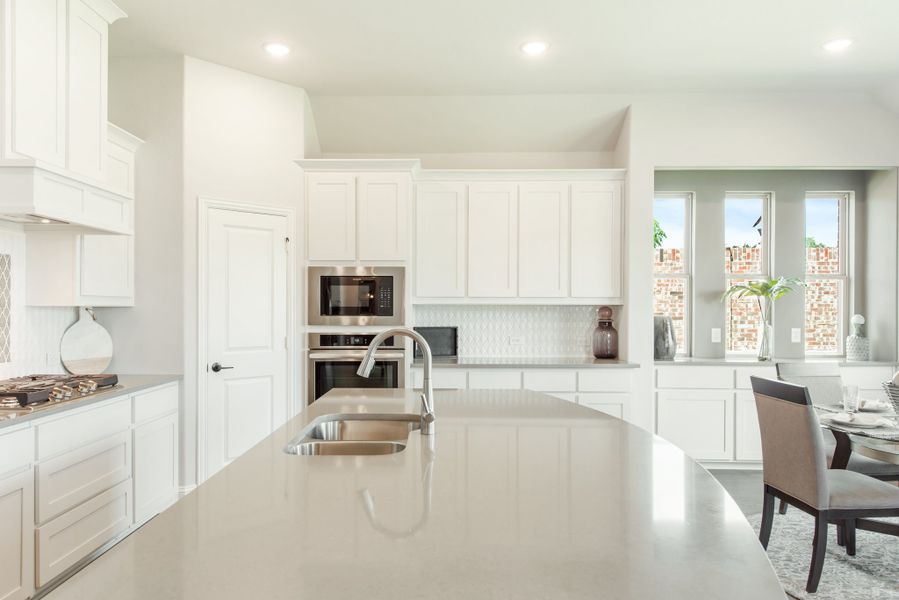 Kitchen with white cabinets, large island with sink, stainless steel appliances, and dining area nearby Kitchen with white cabinets, large island with sink, stainless steel appliances, and dining area nearby