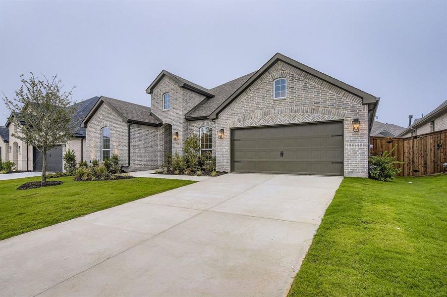 French provincial home featuring brick siding, concrete driveway, an attached garage, and a shingled roof