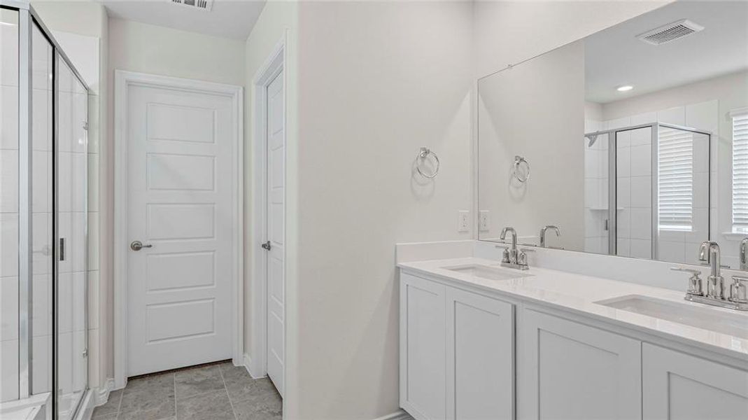 Bathroom featuring a dual vanity with white cabinetry and a full-width mirror
