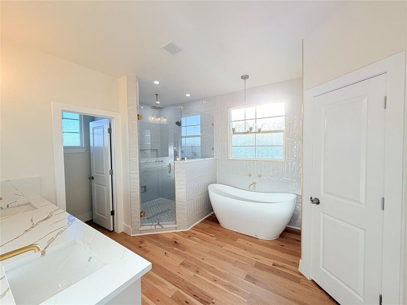 Full bath with vanity, a shower stall, light wood-type flooring, and a freestanding tub Full bath with vanity, a shower stall, light wood-type flooring, and a freestanding tub