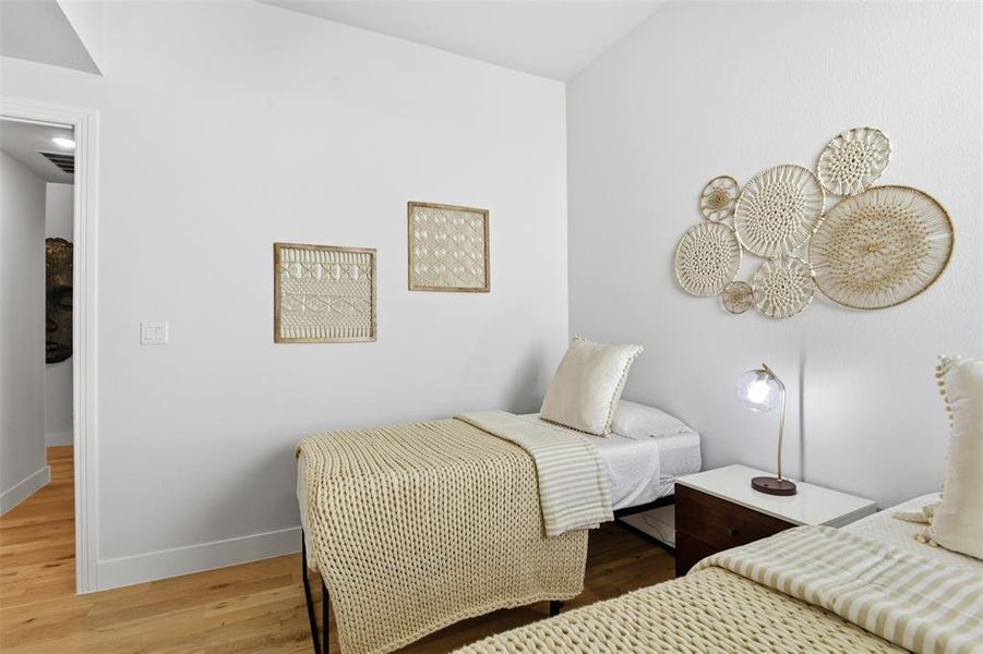 Light-filled room featuring hardwood flooring, white walls, and a vaulted ceiling Light-filled room featuring hardwood flooring, white walls, and a vaulted ceiling
