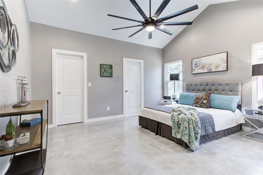 Bedroom with baseboards, high vaulted ceiling, finished concrete flooring, and a ceiling fan