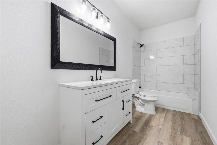 Secondary full bathroom equipped with a wide vanity, large mirror, and tub/shower combo with accent tiling. Secondary full bathroom equipped with a wide vanity, large mirror, and tub/shower combo with accent tiling.
