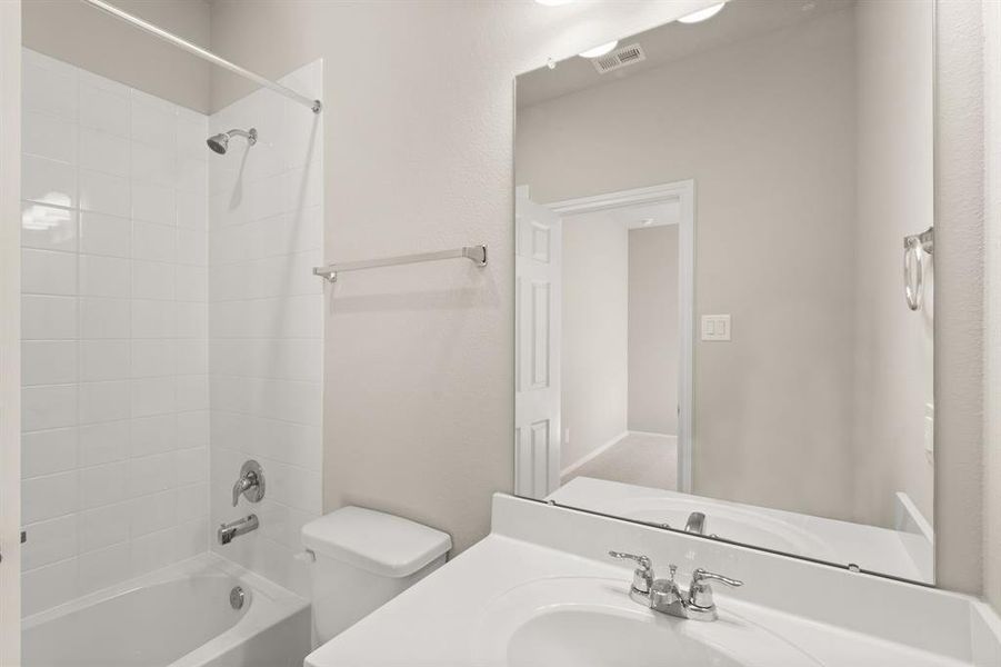 The secondary bath features tile flooring, white cabinetry and light countertops and a shower/tub combo. Perfect for accommodating any visiting family and friends.