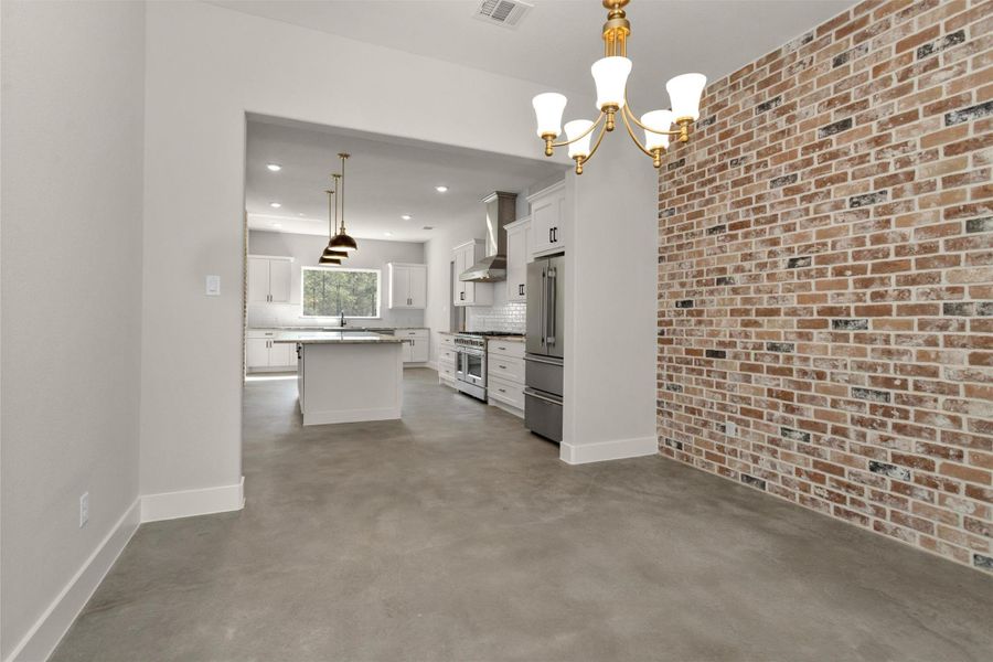 Just off the kitchen, the spacious dining area offers the perfect setting for gatherings both large and intimate. The room is beautifully anchored by a stunning brick accent wall, adding warmth, texture, and timeless character to the space.