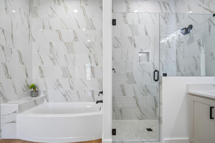 Elegant marble-patterned tile surrounds a deep soaking tub and a glass-enclosed walk-in shower. Elegant marble-patterned tile surrounds a deep soaking tub and a glass-enclosed walk-in shower.