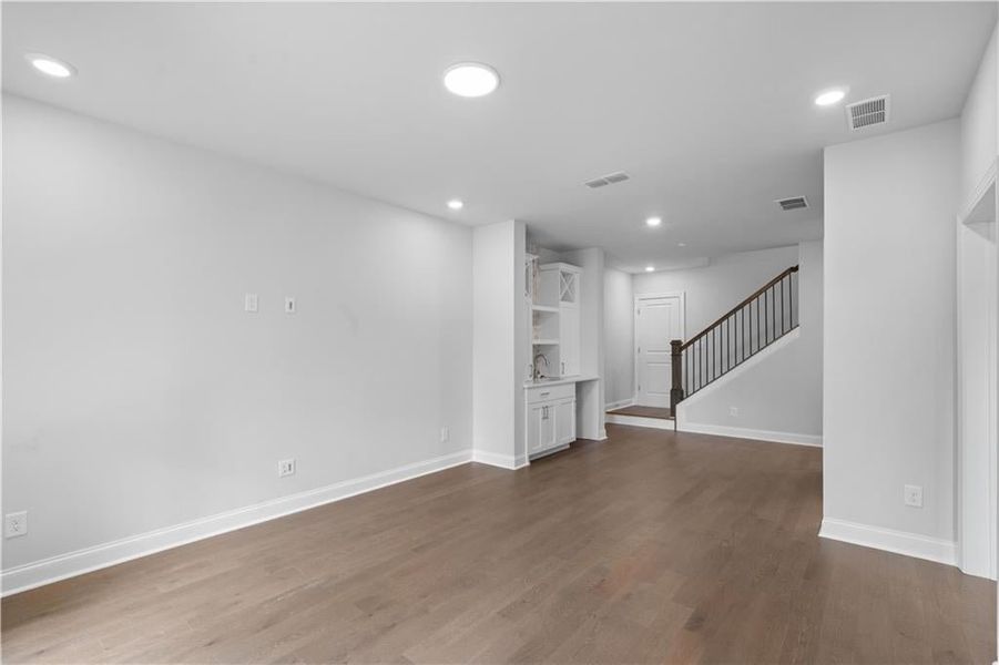 Unfurnished living room featuring dark wood-type flooring, recessed lighting, and stairway Unfurnished living room featuring dark wood-type flooring, recessed lighting, and stairway