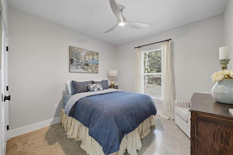 Bedroom featuring a ceiling fan and finished concrete floors Bedroom featuring a ceiling fan and finished concrete floors