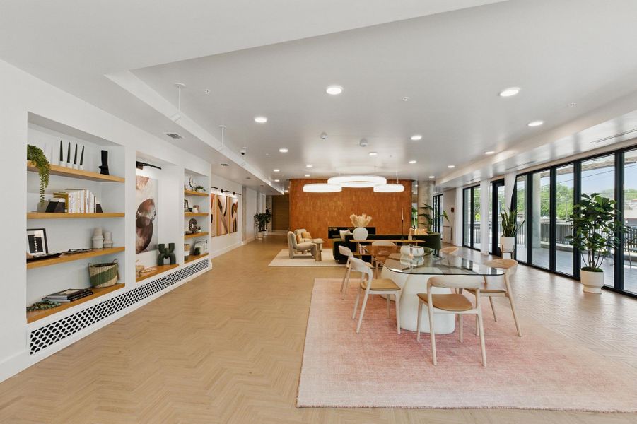 Herringbone wood flooring unifies a modern, open-concept lounge with extensive shelving and patio access.