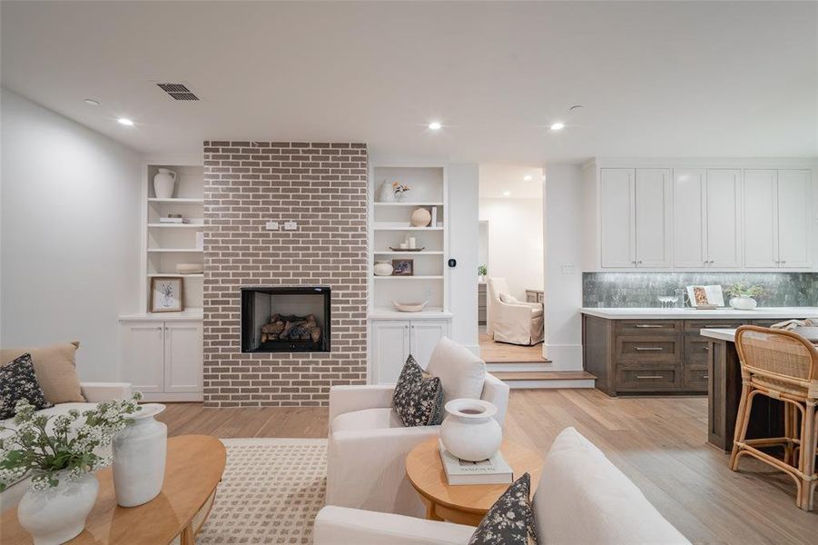 Living room with a fireplace and light wood-type flooring