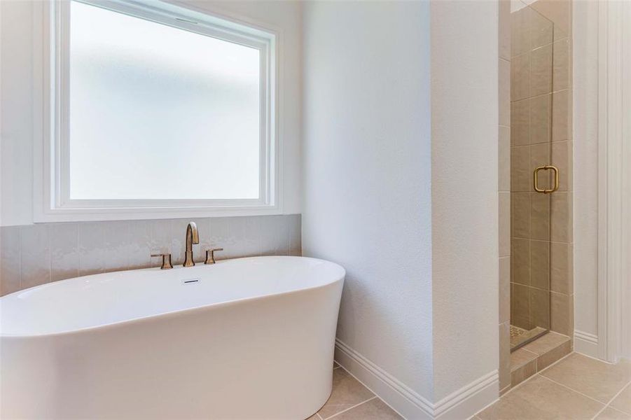 Bathroom featuring tile patterned flooring, shower with separate bathtub, and a healthy amount of sunlight