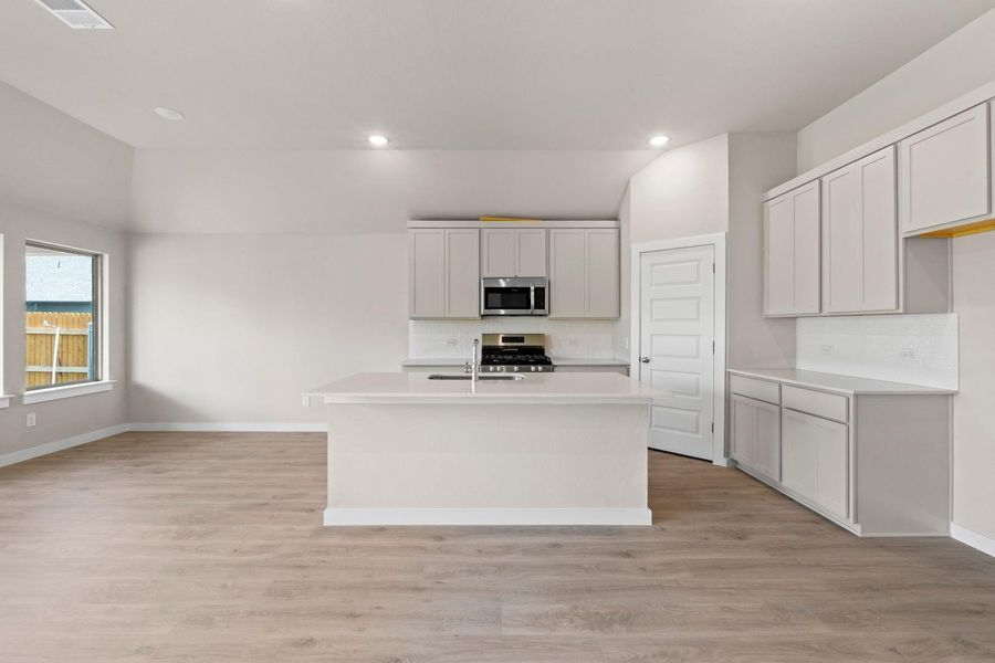 A well-appointed kitchen island anchors this open concept living space, featuring new appliances and light-toned flooring.