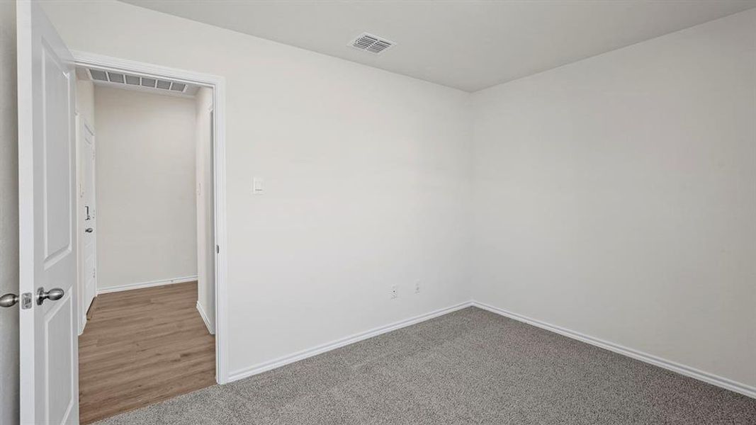 Interior room featuring light gray carpet flooring, white walls, and white baseboards