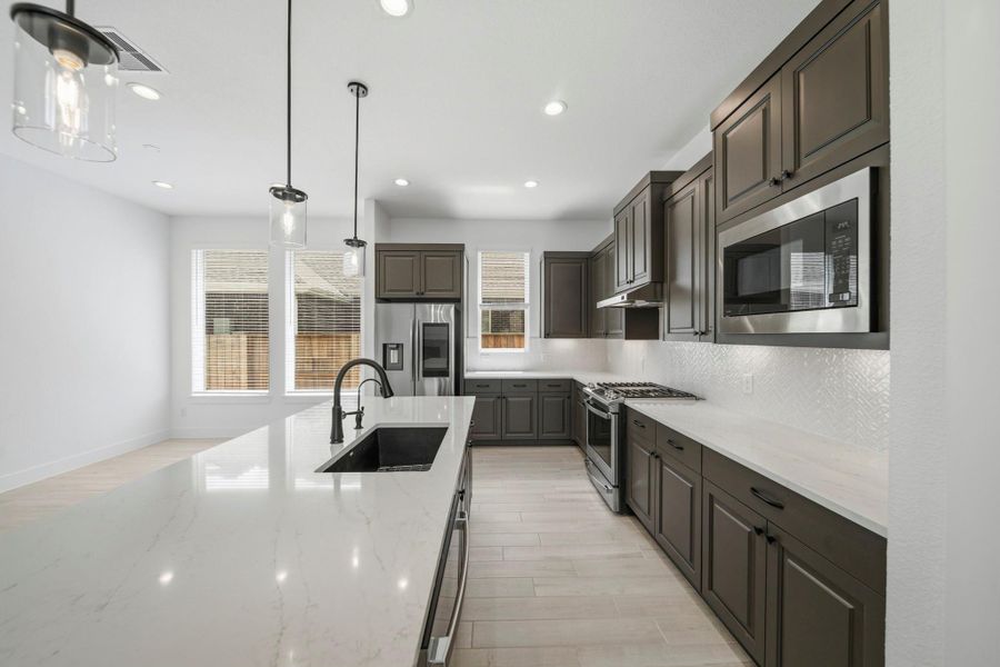 You'll love the details of this kitchen with quartz countertops, under cabinet lighting, a modern tile backsplash, and tons of countertop space!