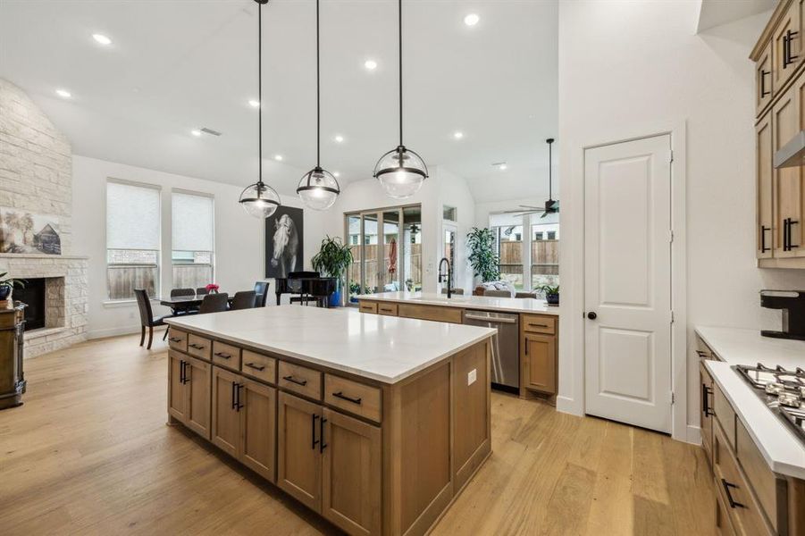 Kitchen featuring stainless steel dishwasher, a kitchen island, open floor plan, light wood-style floors, and brown cabinetry