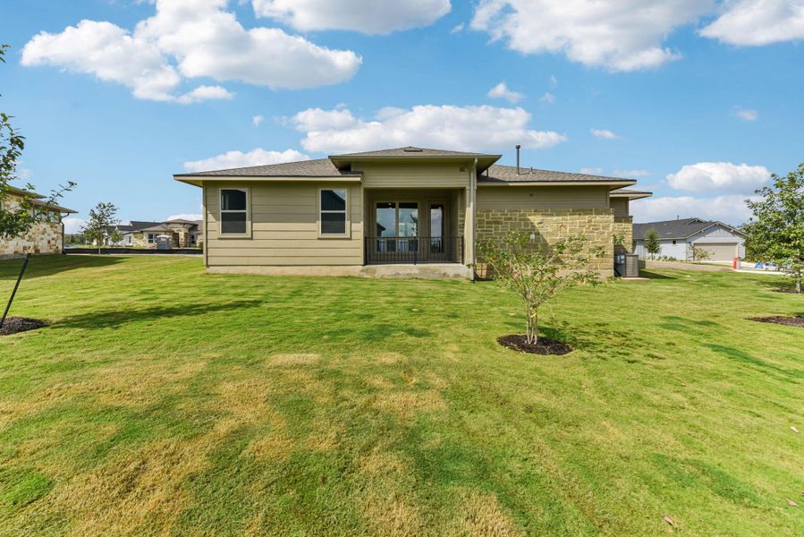 Rear view of house featuring a lawn, a patio, and roof with shingles