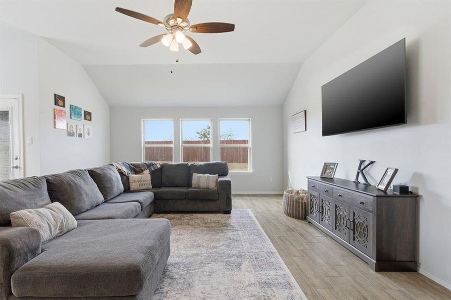 Living room with wood tiled floors, lofted ceiling, and ceiling fan