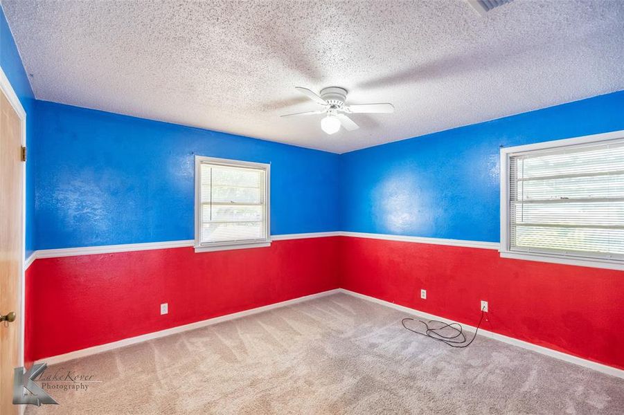 Unfurnished room featuring a textured ceiling, ceiling fan, and carpet