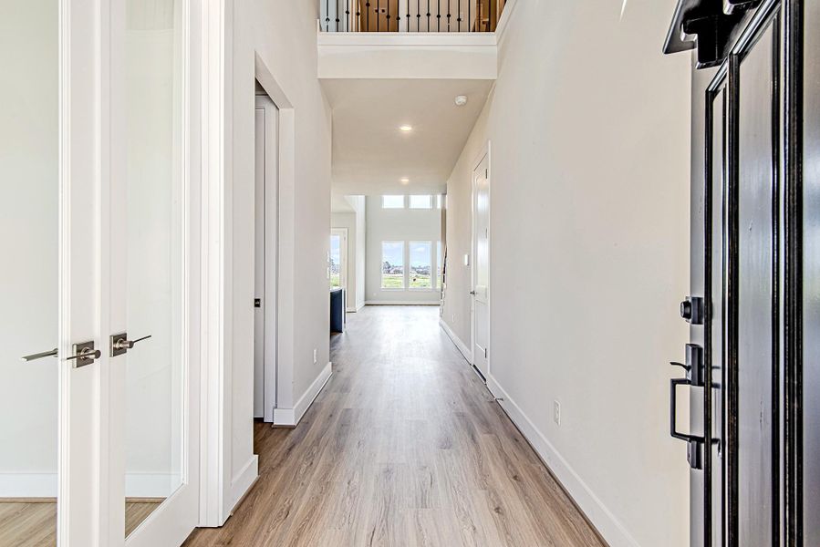 Step inside to a dramatic, light-filled foyer with soaring ceilings and wood-style flooring that flows seamlessly into the main living space. Natural light pours in through the rear windows, drawing the eye toward the backyard views. Step inside to a dramatic, light-filled foyer with soaring ceilings and wood-style flooring that flows seamlessly into the main living space. Natural light pours in through the rear windows, drawing the eye toward the backyard views.