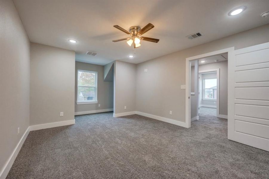 Empty room featuring healthy amount of natural light, light colored carpet, recessed lighting, and ceiling fan