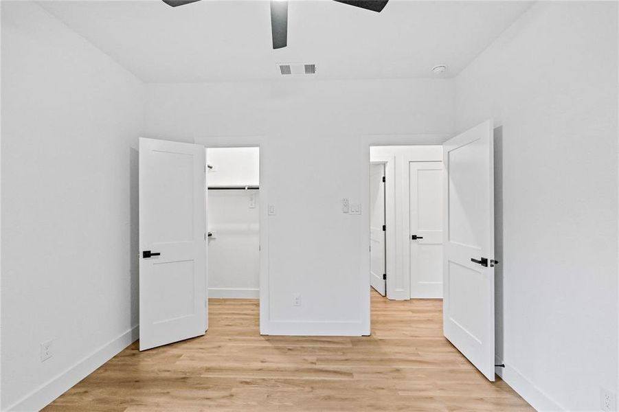 Unfurnished bedroom with a closet, light hardwood / wood-style flooring, a spacious closet, and ceiling fan