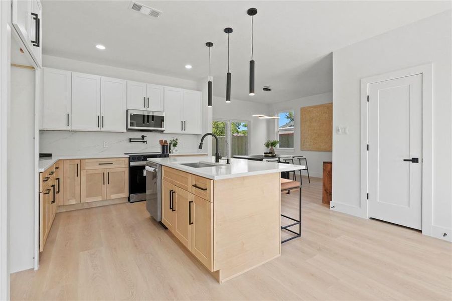 Kitchen with a center island with sink, pendant lighting, recessed lighting, light wood finished floors, and a kitchen bar Kitchen with a center island with sink, pendant lighting, recessed lighting, light wood finished floors, and a kitchen bar