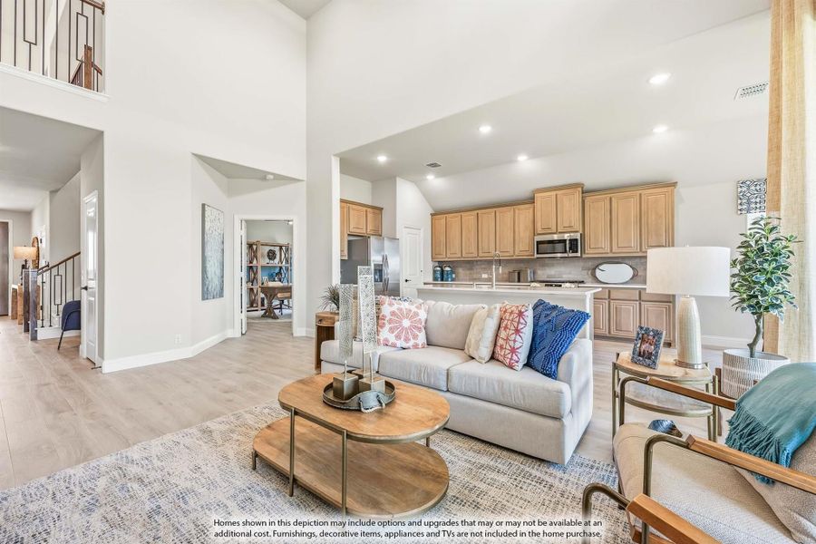 Open-concept living room with high ceilings, hardwood floors, and kitchen visible in background