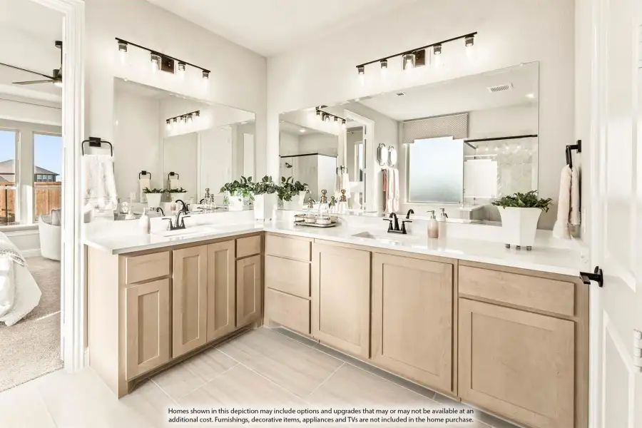 Master bathroom with dual vanity sinks, light wood cabinets, white countertops, and large mirrors with modern lighting