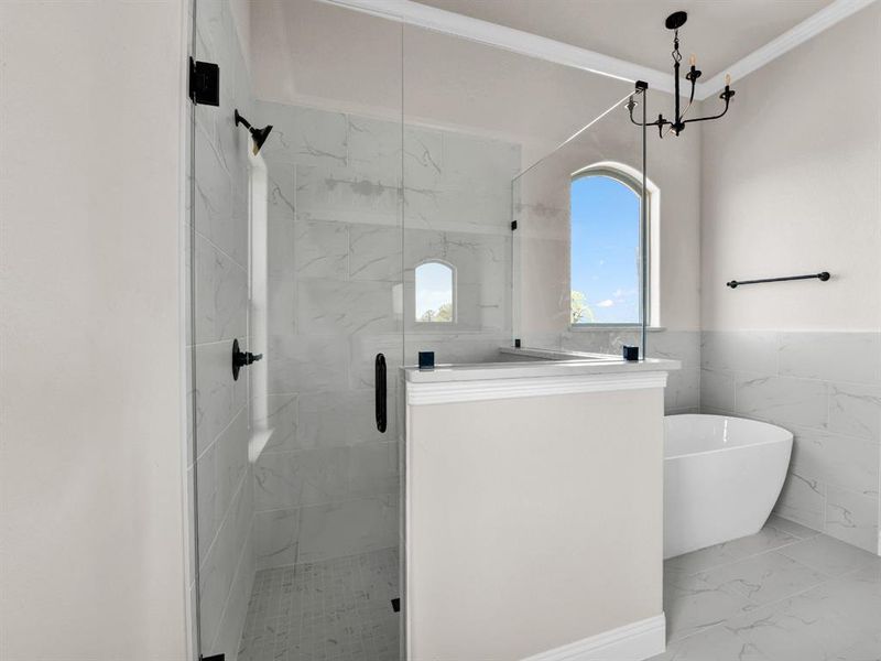 Bathroom featuring a stall shower, marble finish floor, a freestanding bath, ornamental molding, and tile walls Bathroom featuring a stall shower, marble finish floor, a freestanding bath, ornamental molding, and tile walls