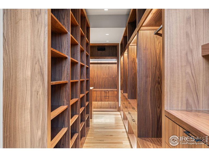 Expansive walk-in closet offers custom walnut built-in cabinetry