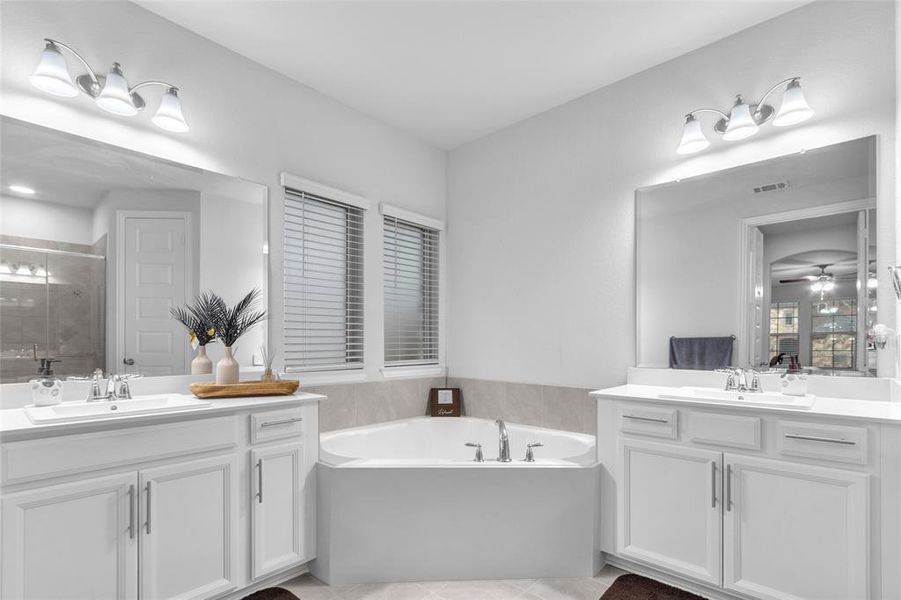 Bathroom featuring a garden tub, a shower stall, visible vents, and a sink