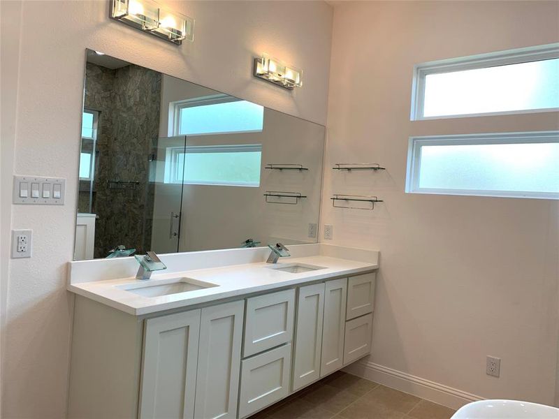 Full bath with a stall shower, double vanity, and dark tile patterned flooring Full bath with a stall shower, double vanity, and dark tile patterned flooring