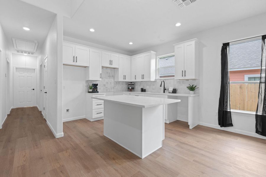 Kitchen featuring a center island, decorative backsplash, light wood-style floors, white cabinets, and recessed lighting