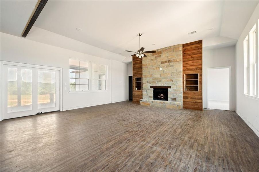 Unfurnished living room featuring built in features, dark hardwood / wood-style flooring, ceiling fan, a fireplace, and high vaulted ceiling