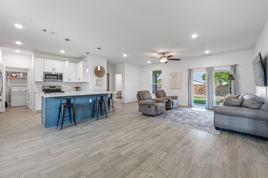Living area featuring light wood finished floors, washer / dryer, ceiling fan, and recessed lighting