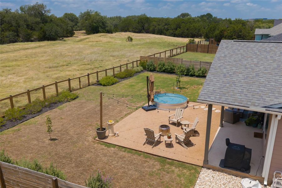 An inviting outdoor living space features a stock tank pool and patio, complementing the expansive fenced yard.
