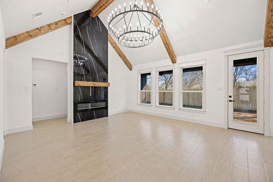 Unfurnished living room featuring beamed ceiling, wood finished floors, visible vents, and baseboards