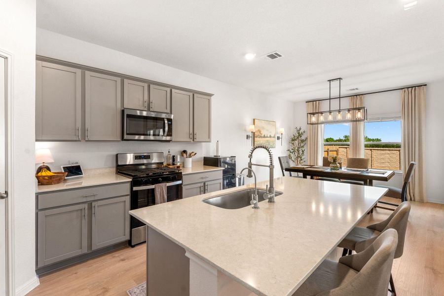 An inviting kitchen with light gray cabinetry and an ample island seamlessly transitions into a dining area. An inviting kitchen with light gray cabinetry and an ample island seamlessly transitions into a dining area.