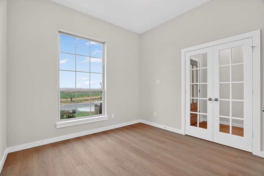 Room featuring wood-finish flooring, light grey walls, and white baseboards