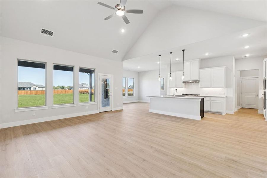 Unfurnished living room with high vaulted ceiling, light wood-style floors, recessed lighting, and a ceiling fan
