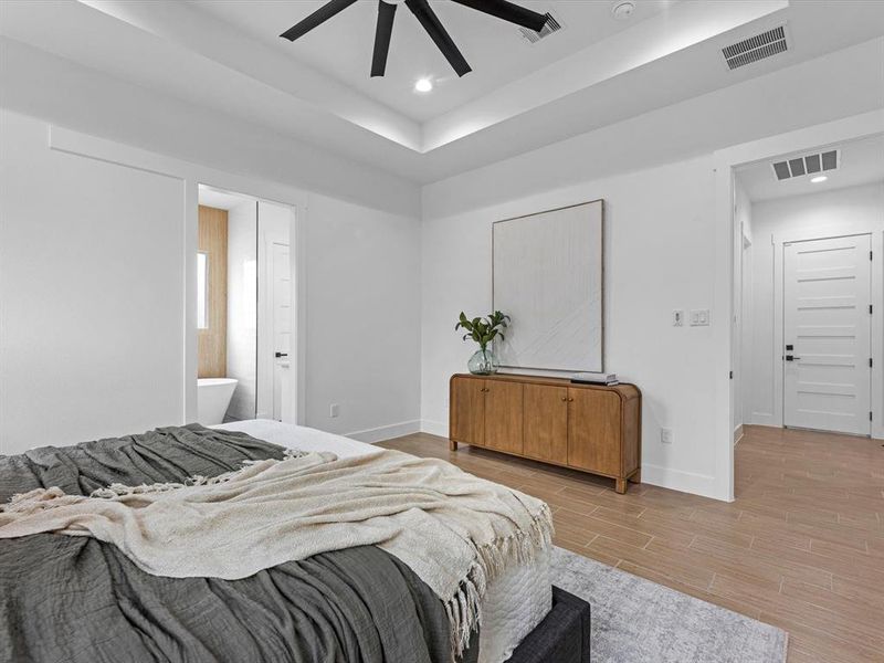 Primary bedroom features include; ceiling fan, tray ceiling, and tile flooring